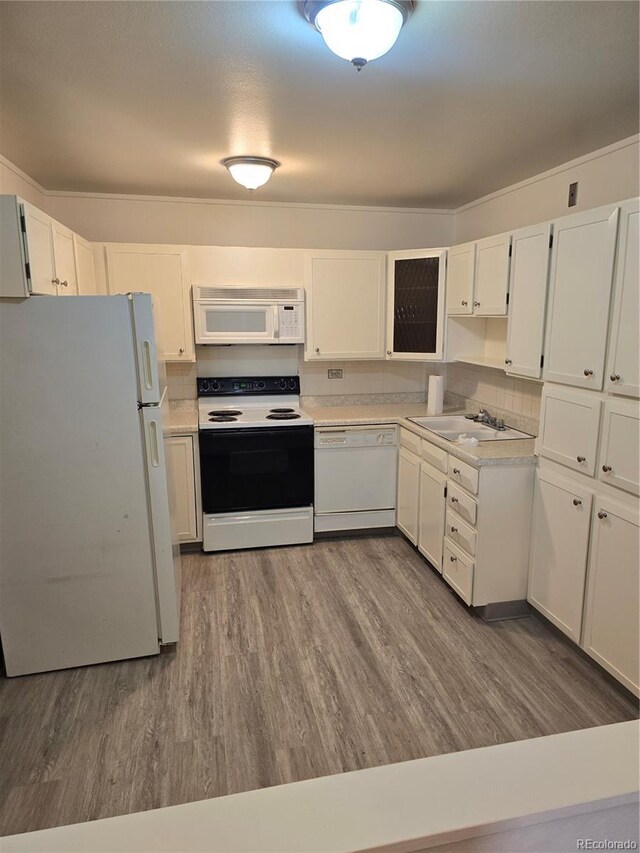 kitchen with white cabinets, wood-type flooring, white appliances, and sink