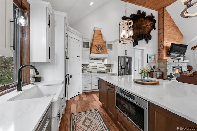 663 Brookside Dr, Bailey, CO 80421 - kitchen featuring stainless steel fridge, custom exhaust hood, high vaulted ceiling, glass insert cabinets, and black electric cooktop