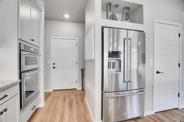 10912 Memphis Ct, Commerce City, CO 80022 - kitchen featuring appliances with stainless steel finishes, light wood finished floors, baseboards, white cabinets, and recessed lighting