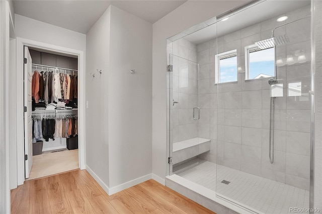 10912 Memphis Ct, Commerce City, CO 80022 - bathroom featuring a shower stall, wood finished floors, a walk in closet, and baseboards