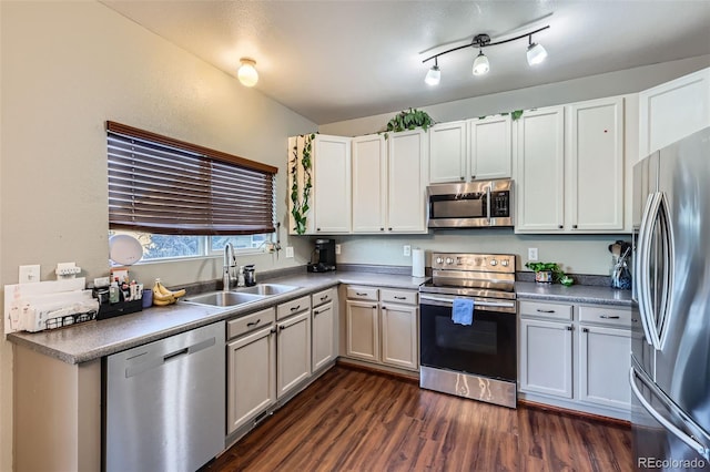 kitchen with appliances with stainless steel finishes, white cabinetry, dark wood-type flooring, and sink