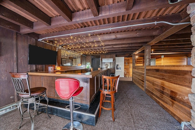 bar with wooden walls, beamed ceiling, a bar, and dark colored carpet