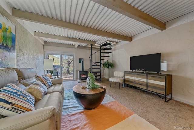 living room with carpet floors, stairway, beam ceiling, and a wood stove