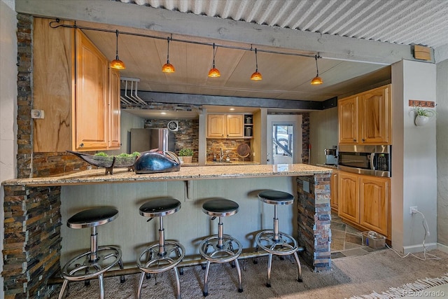 kitchen with a breakfast bar area, stainless steel appliances, tasteful backsplash, and a peninsula