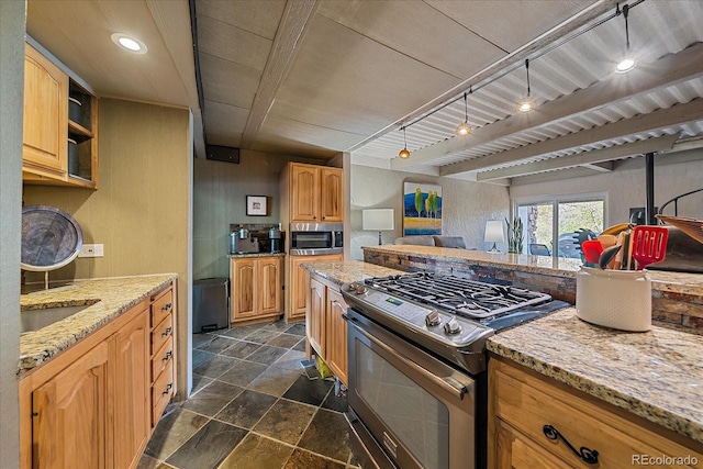 kitchen featuring appliances with stainless steel finishes, light stone counters, a sink, open floor plan, and stone finish flooring