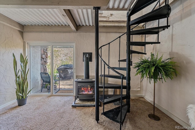 staircase featuring carpet flooring, baseboards, and a wood stove