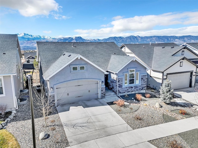 view of front of property featuring stucco siding, a mountain view, driveway, and roof with shingles