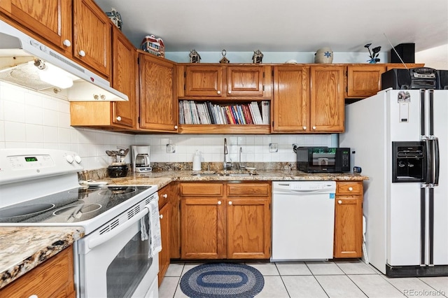 2516 S Cimarron St, Aurora, CO 80014 - kitchen with white appliances, under cabinet range hood, light tile patterned floors, and brown cabinets