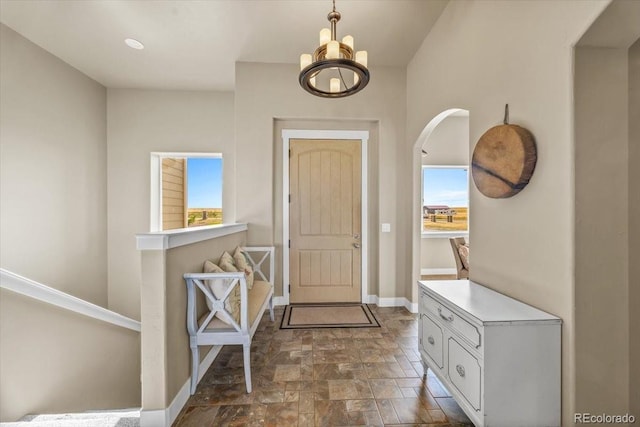 45425 Wolf Creek Dr, Bennett, CO 80102 - entryway featuring stone finish floors, a chandelier, and arched walkways