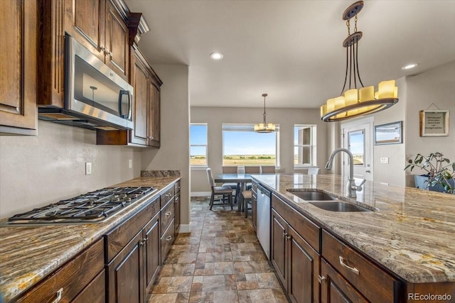 45425 Wolf Creek Dr, Bennett, CO 80102 - kitchen with stainless steel appliances, dark stone finish floors, a chandelier, healthy amount of natural light, and recessed lighting