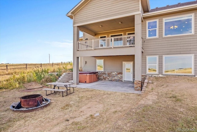 45425 Wolf Creek Dr, Bennett, CO 80102 - back of property featuring a hot tub, an outdoor fire pit, a balcony, a patio, and stone siding