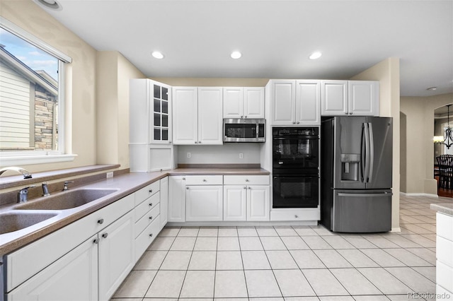 6427 S Tibet St, Aurora, CO 80016 - kitchen with appliances with stainless steel finishes, white cabinetry, light tile patterned flooring, recessed lighting, and glass insert cabinets