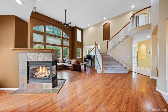 6427 S Tibet St, Aurora, CO 80016 - living room featuring a fireplace, a towering ceiling, stairway, wood finished floors, and ceiling fan