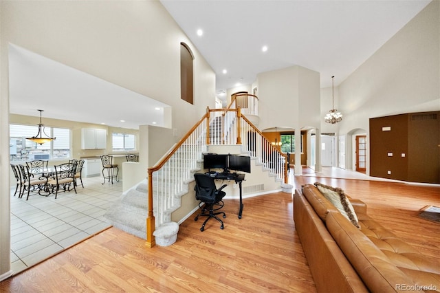 6427 S Tibet St, Aurora, CO 80016 - living room featuring stairway, a high ceiling, light wood-style floors, arched walkways, and recessed lighting