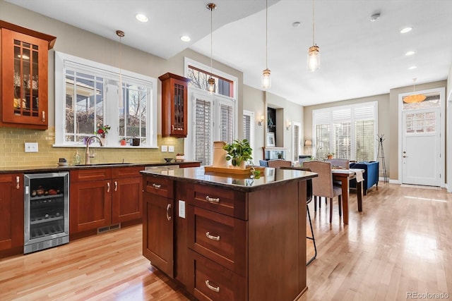 kitchen featuring light wood finished floors, a breakfast bar area, a sink, tasteful backsplash, and wine cooler