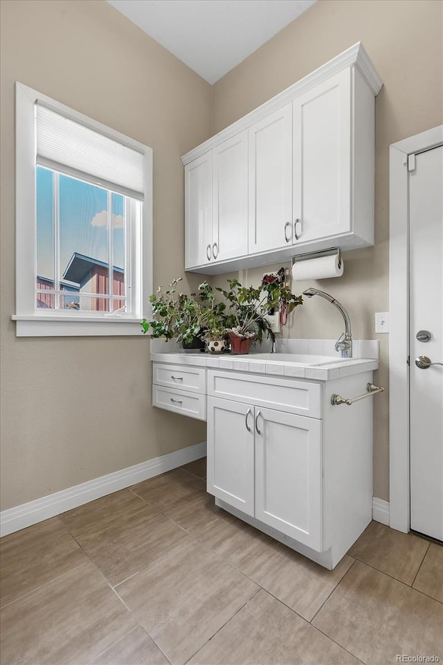 interior space with baseboards, light tile patterned flooring, and a sink
