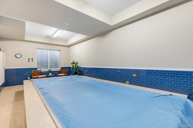 interior space with a tray ceiling and a wainscoted wall