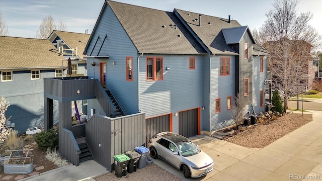 exterior space featuring roof with shingles, stairs, and an attached garage