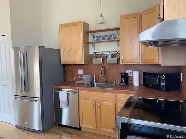 kitchen with under cabinet range hood, appliances with stainless steel finishes, light brown cabinets, and a sink