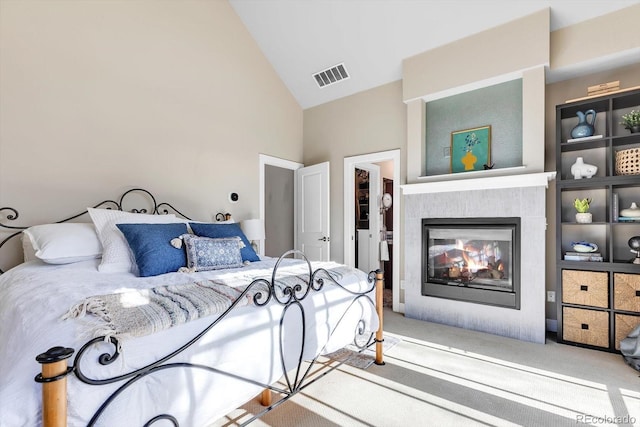 carpeted bedroom with a fireplace, visible vents, and high vaulted ceiling