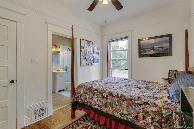 bedroom featuring visible vents, ceiling fan, ensuite bathroom, wood finished floors, and a sink