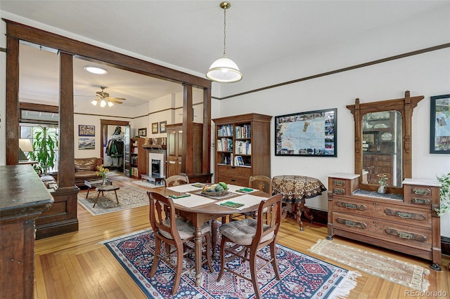 dining space featuring a fireplace, a ceiling fan, and light wood-type flooring