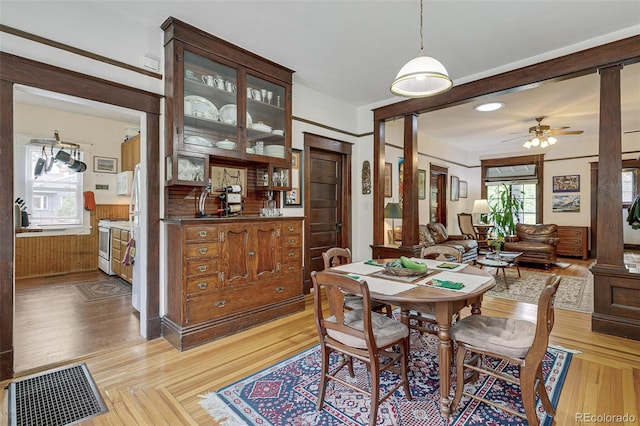 dining area with visible vents, decorative columns, ceiling fan, wainscoting, and light wood-type flooring