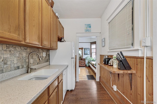 kitchen featuring a wainscoted wall, dark wood-style flooring, a sink, tasteful backsplash, and brown cabinets