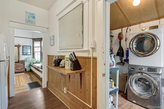 laundry area featuring stacked washer and dryer, wood finished floors, and laundry area