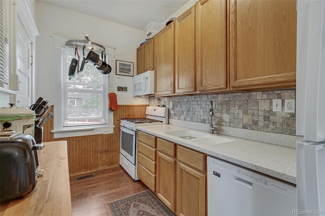 kitchen featuring tasteful backsplash, light countertops, wood finished floors, white appliances, and a sink