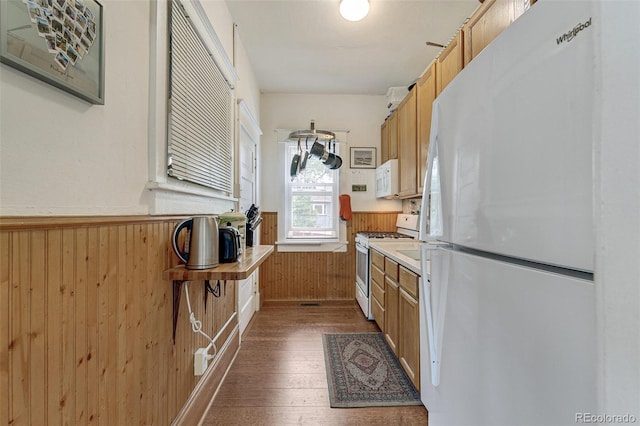 kitchen featuring white appliances, a wainscoted wall, wood walls, and dark wood-type flooring