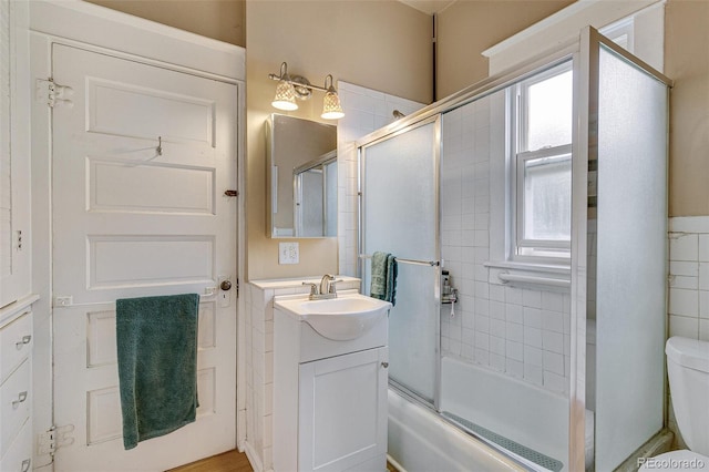 bathroom featuring vanity, toilet, and enclosed tub / shower combo