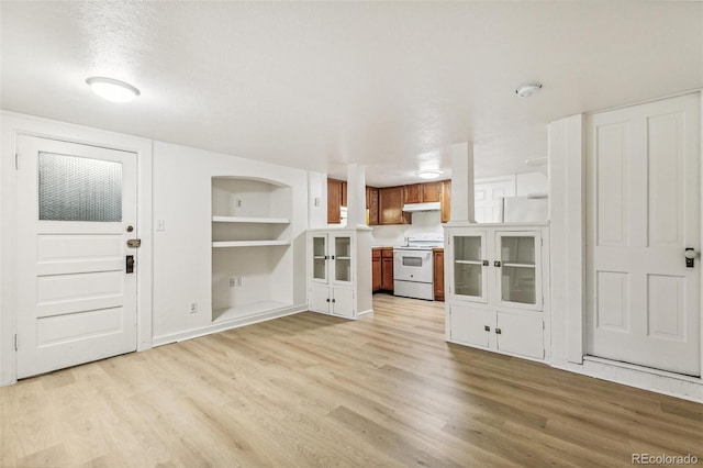 unfurnished living room with built in features and light wood-type flooring