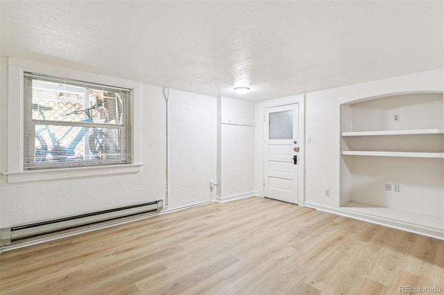 unfurnished room with built in shelves, baseboard heating, wood finished floors, and a textured ceiling