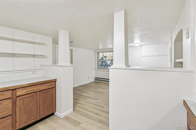 kitchen with light wood finished floors, decorative columns, a textured ceiling, a baseboard heating unit, and brown cabinets