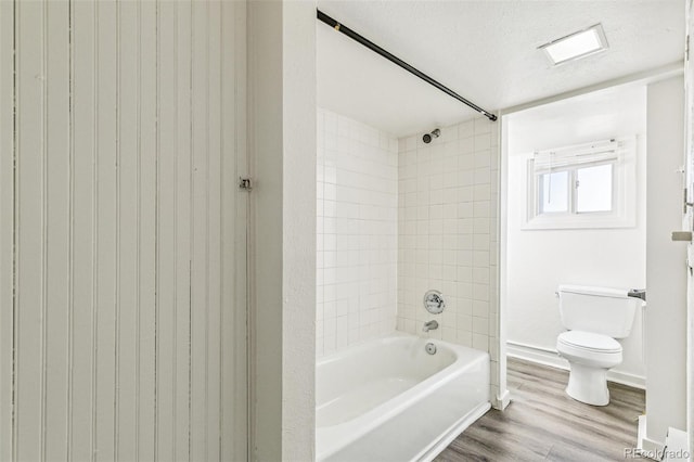 full bathroom featuring baseboards, toilet, wood finished floors, a textured ceiling, and washtub / shower combination