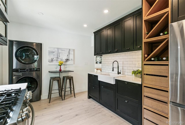 3625 W 9th Ave, Denver, CO 80204 - kitchen with stacked washer / drying machine, a sink, tasteful backsplash, stainless steel appliances, and light countertops