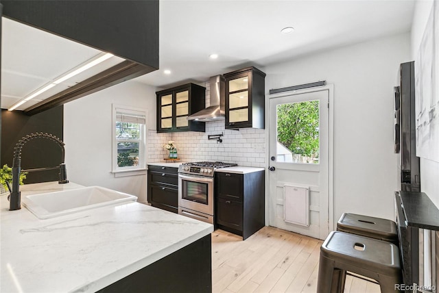 3625 W 9th Ave, Denver, CO 80204 - kitchen with stainless steel range with gas stovetop, wall chimney exhaust hood, a sink, light wood-style flooring, and backsplash