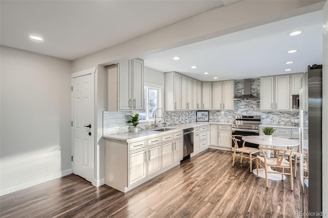 kitchen with a sink, stainless steel appliances, dark wood-style floors, and wall chimney range hood