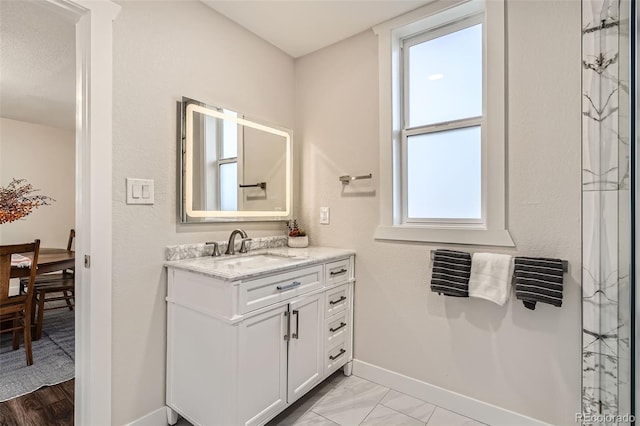 full bath featuring baseboards and vanity