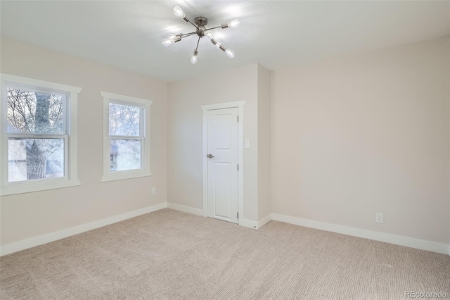 empty room featuring baseboards, light carpet, and a notable chandelier