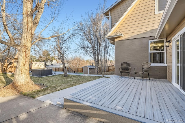 wooden terrace with a lawn, a storage shed, a fenced backyard, an outdoor structure, and a jacuzzi