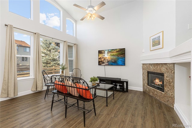 dining area with a tile fireplace, ceiling fan, high vaulted ceiling, and dark wood-type flooring