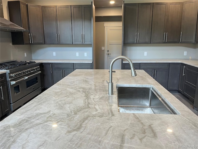 485 Cardiff Cir, Colorado Springs, CO 80906 - kitchen with double oven range, wall chimney exhaust hood, a sink, dark brown cabinetry, and light stone countertops
