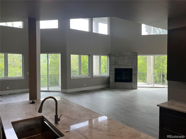 485 Cardiff Cir, Colorado Springs, CO 80906 - unfurnished living room featuring a sink, healthy amount of natural light, a towering ceiling, and baseboards