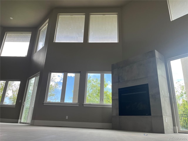 485 Cardiff Cir, Colorado Springs, CO 80906 - unfurnished living room featuring plenty of natural light, a tiled fireplace, a high ceiling, and baseboards
