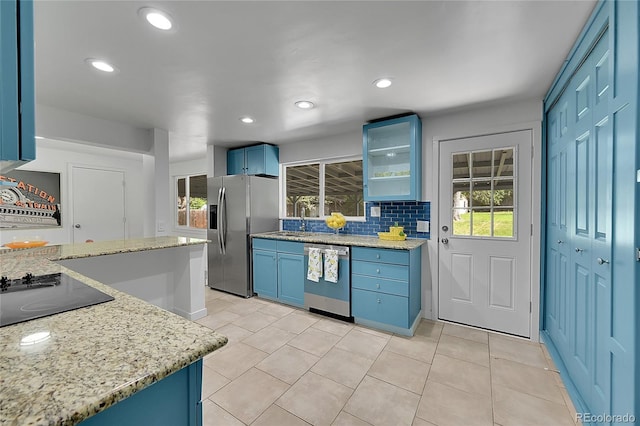 1552 W Caley Ave, Littleton, CO 80120 - kitchen featuring stainless steel appliances, blue cabinets, light stone countertops, tasteful backsplash, and light tile patterned floors