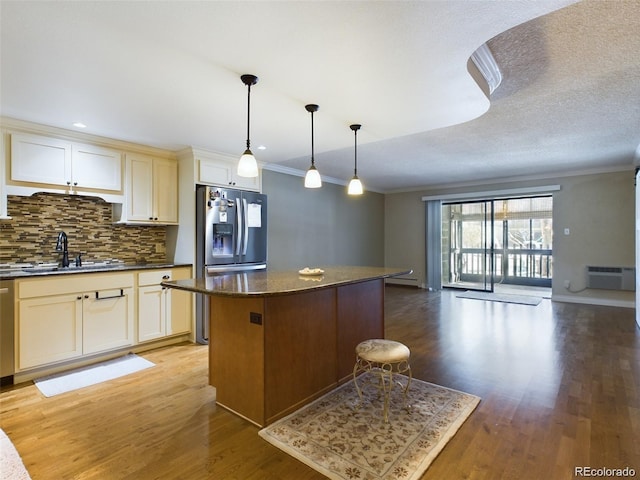 kitchen with sink, crown molding, hanging light fixtures, a center island, and dark stone counters