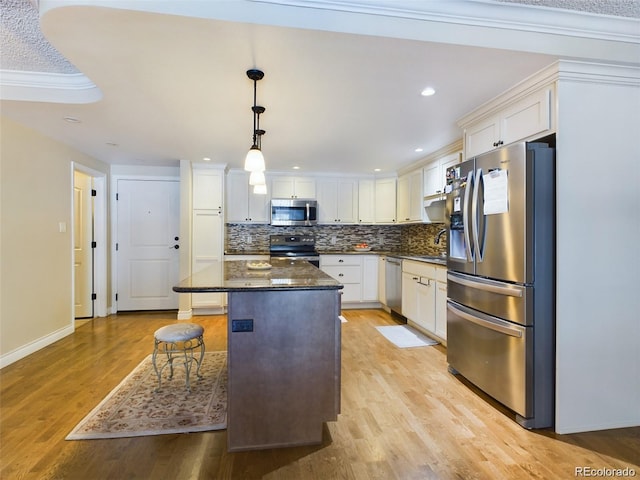 kitchen with pendant lighting, dark stone countertops, stainless steel appliances, white cabinets, and a kitchen island