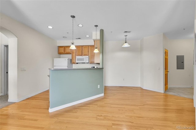 kitchen featuring light wood-type flooring, visible vents, white appliances, arched walkways, and hanging light fixtures